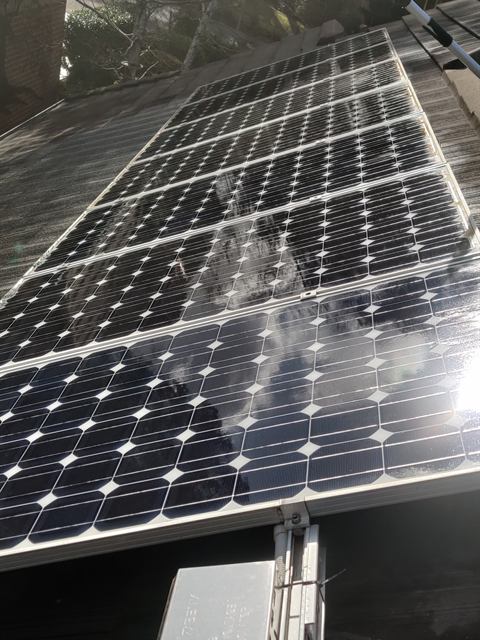 Solar array on a dark roof, viewed along the panel row
