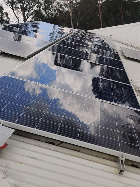 Row of solar panels reflecting gum trees and open sky